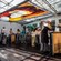Visitantes de Disney Cruise Line con delantales puestos preparan postres en una amplia cocina